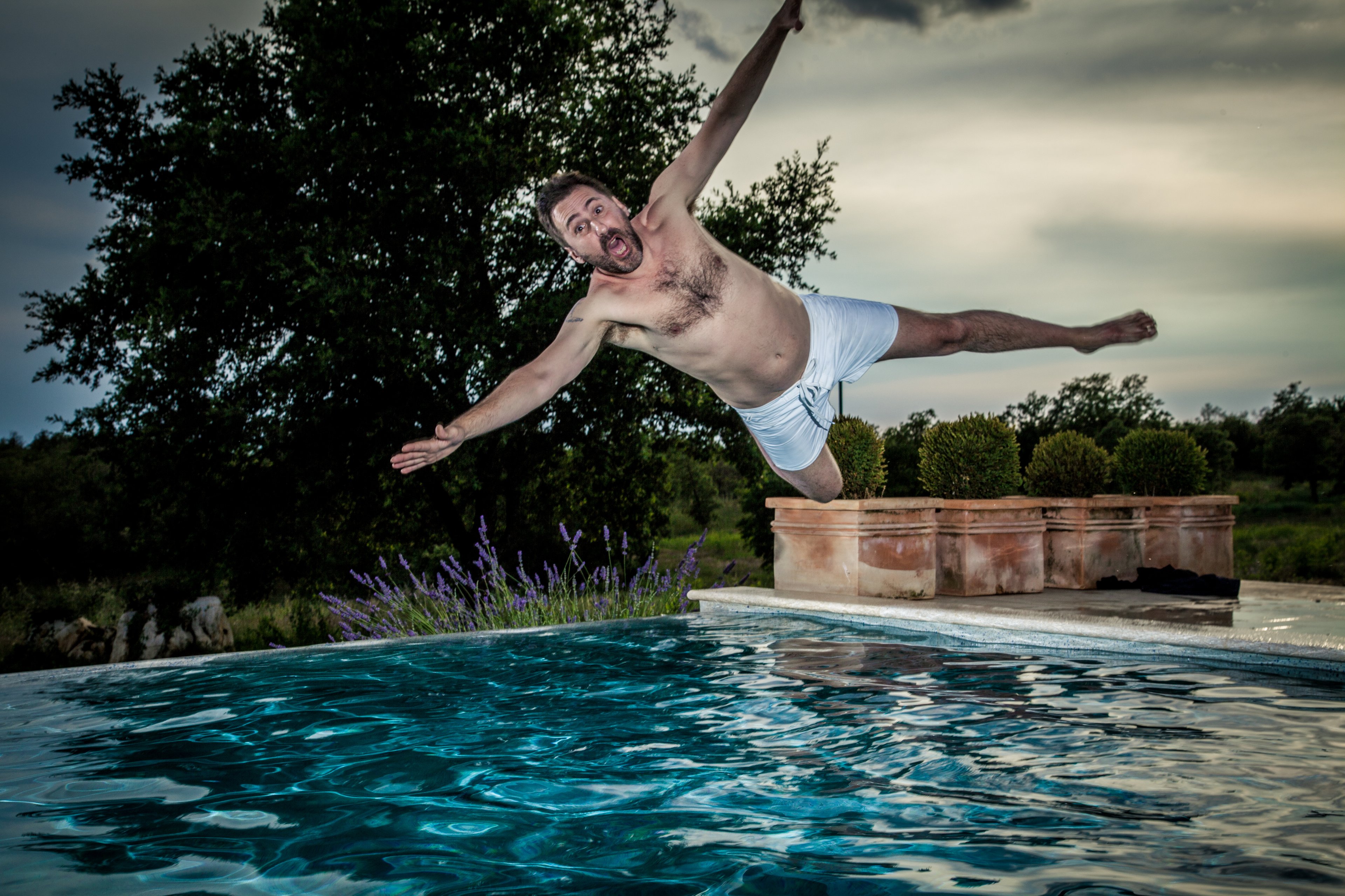 A man jumps sideways into pool. 