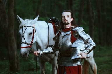 Knight in armor posing next to a white horse