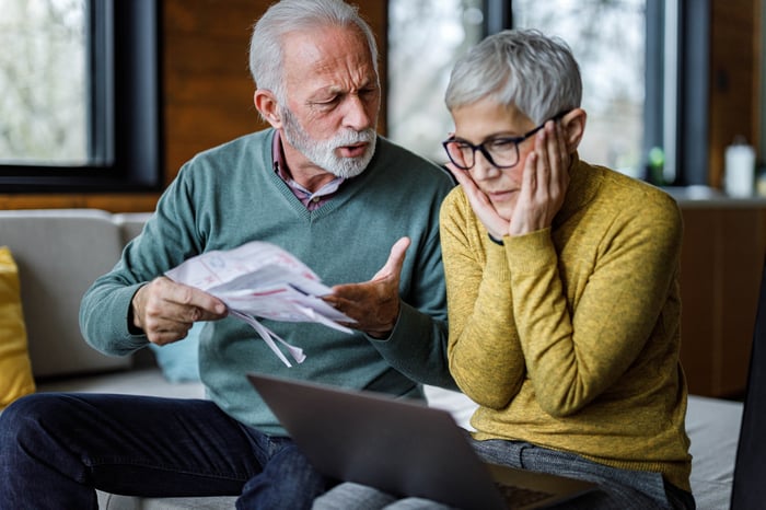 Two people looking upset with one holding documents. 