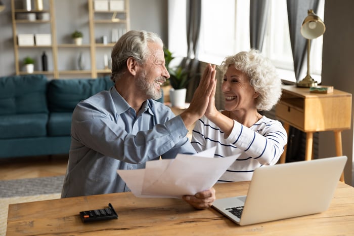 Two people hold documents and give high fives.