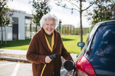 senior citizen charges an electric car.