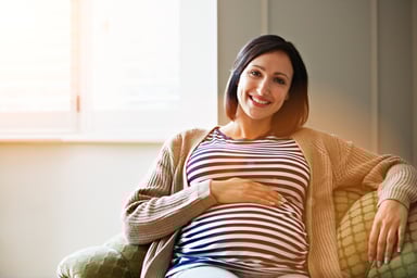 Getty - pregnant happy smiling on couch