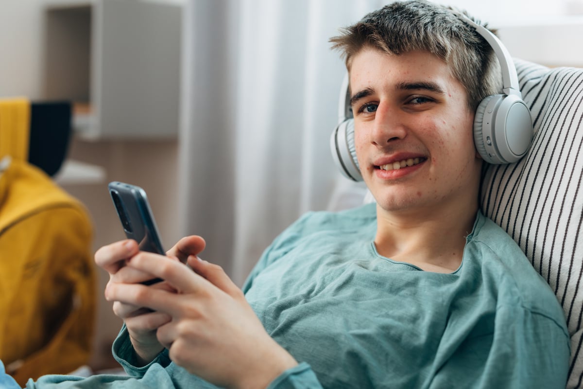 A person wearing wireless headphones and holding a mobile device.