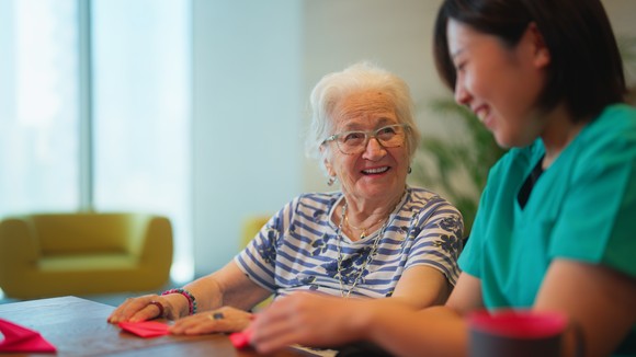 A person wearing scrubs sits at a table with another person.