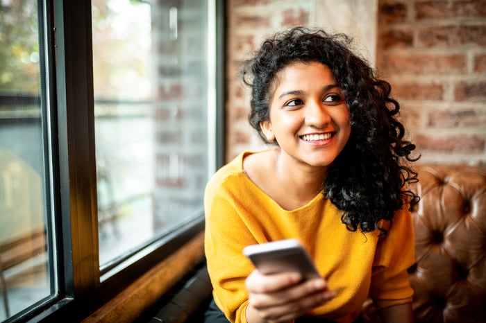 Smiling person holding smartphone.