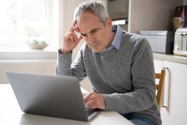 Person using laptop looking concerned 1295467805