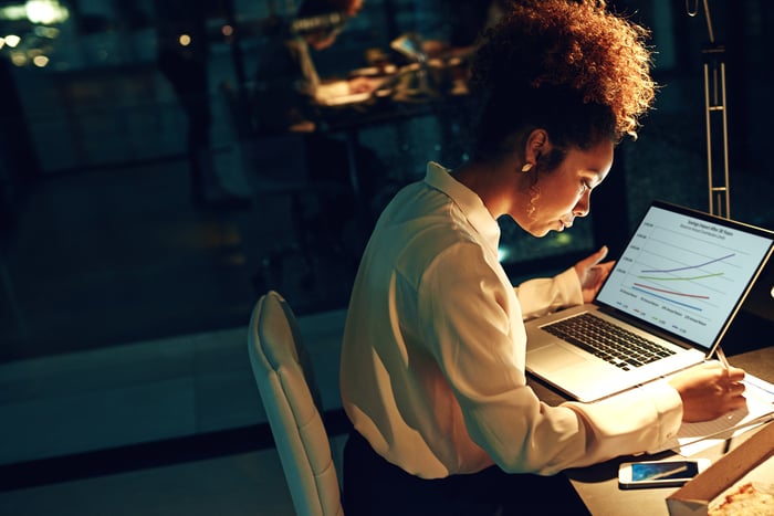 A person works at a computer in a darkened office.