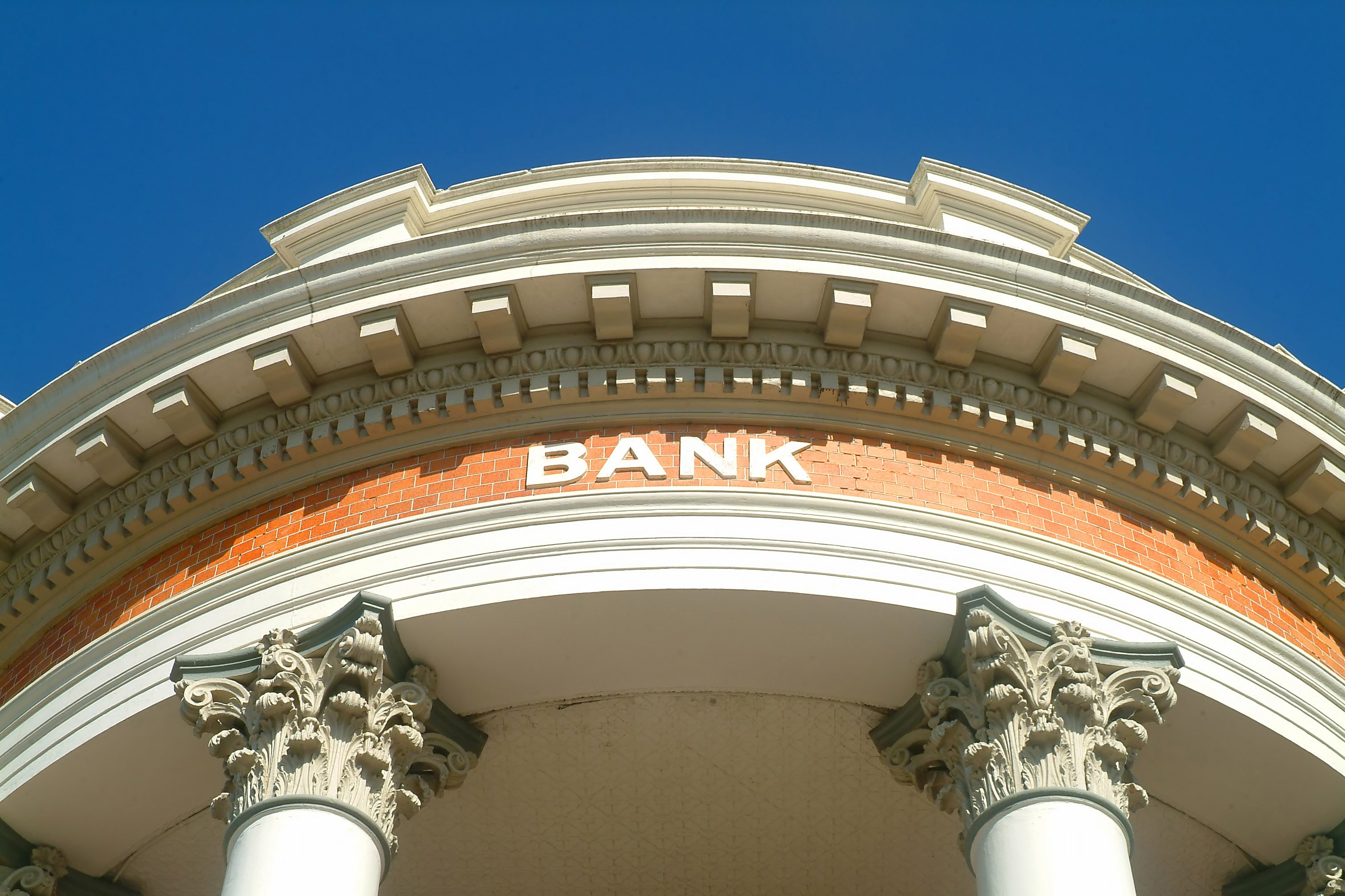 A brick building with columns and the word Bank on the facade.