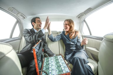 Two people celebrating with cash in a car
