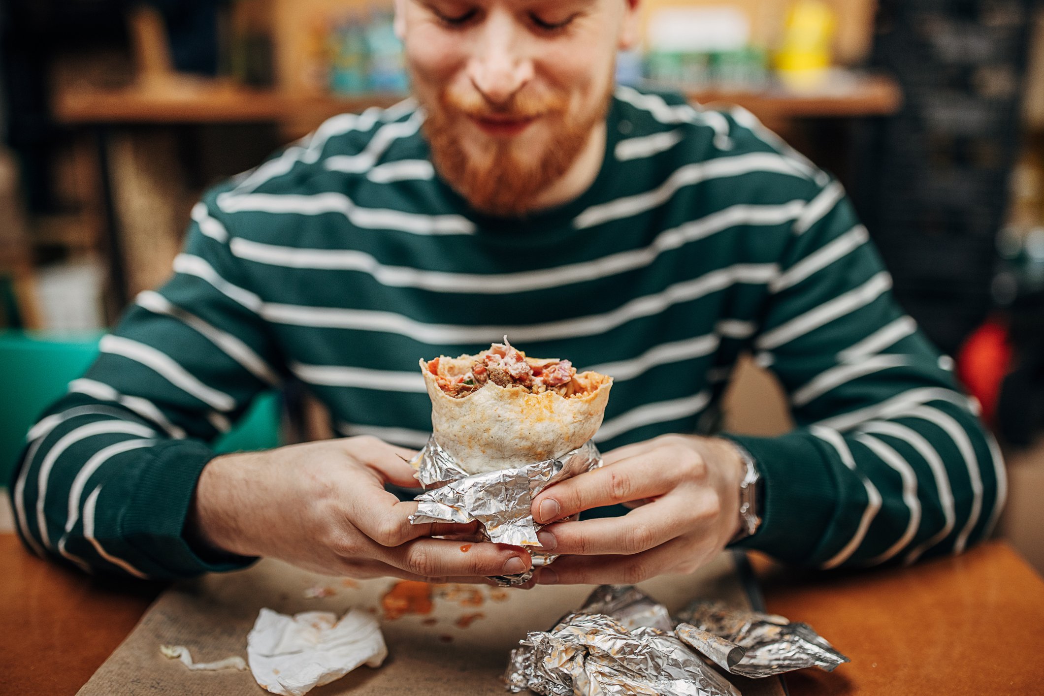 A person eats a burrito in a Chipotle restaurant.