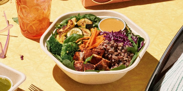 A Sweetgreen salad bowl sits on a table.