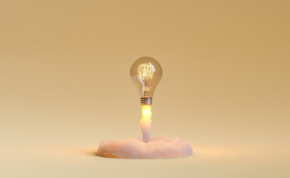 A lightbulb taking off like a rocket on a golden background.