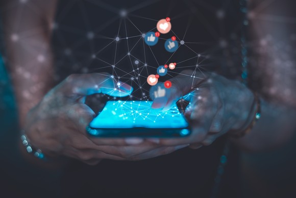 Rendering of a person holding a phone with various apps and connecting lines emitting from the phone.