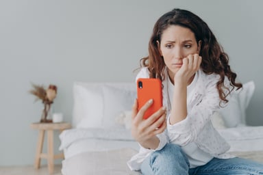 Concerned woman looks at a smartphone.