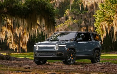 Rivian SUV among oak trees