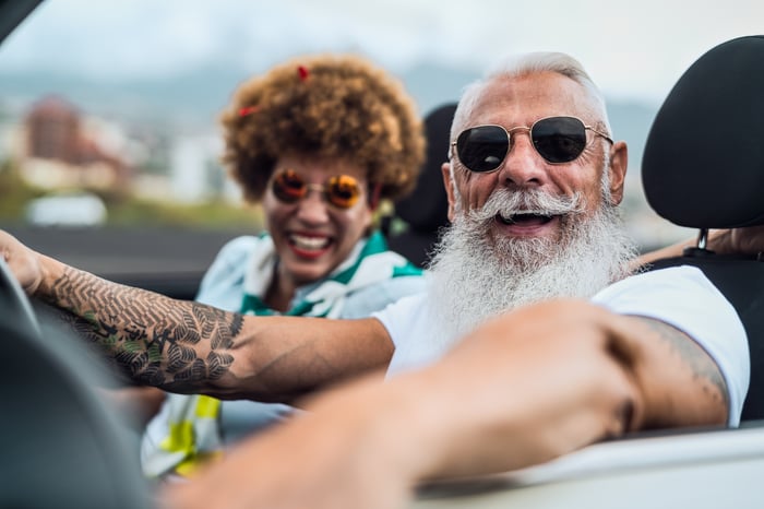 Two smiling people in a convertible.