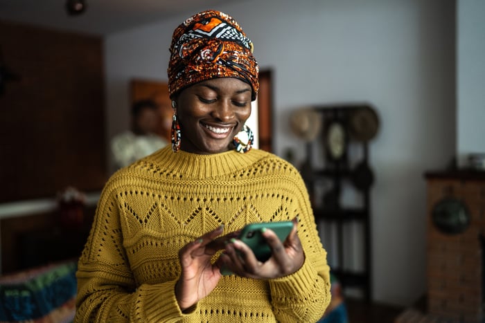 Smiling person looking at smartphone.