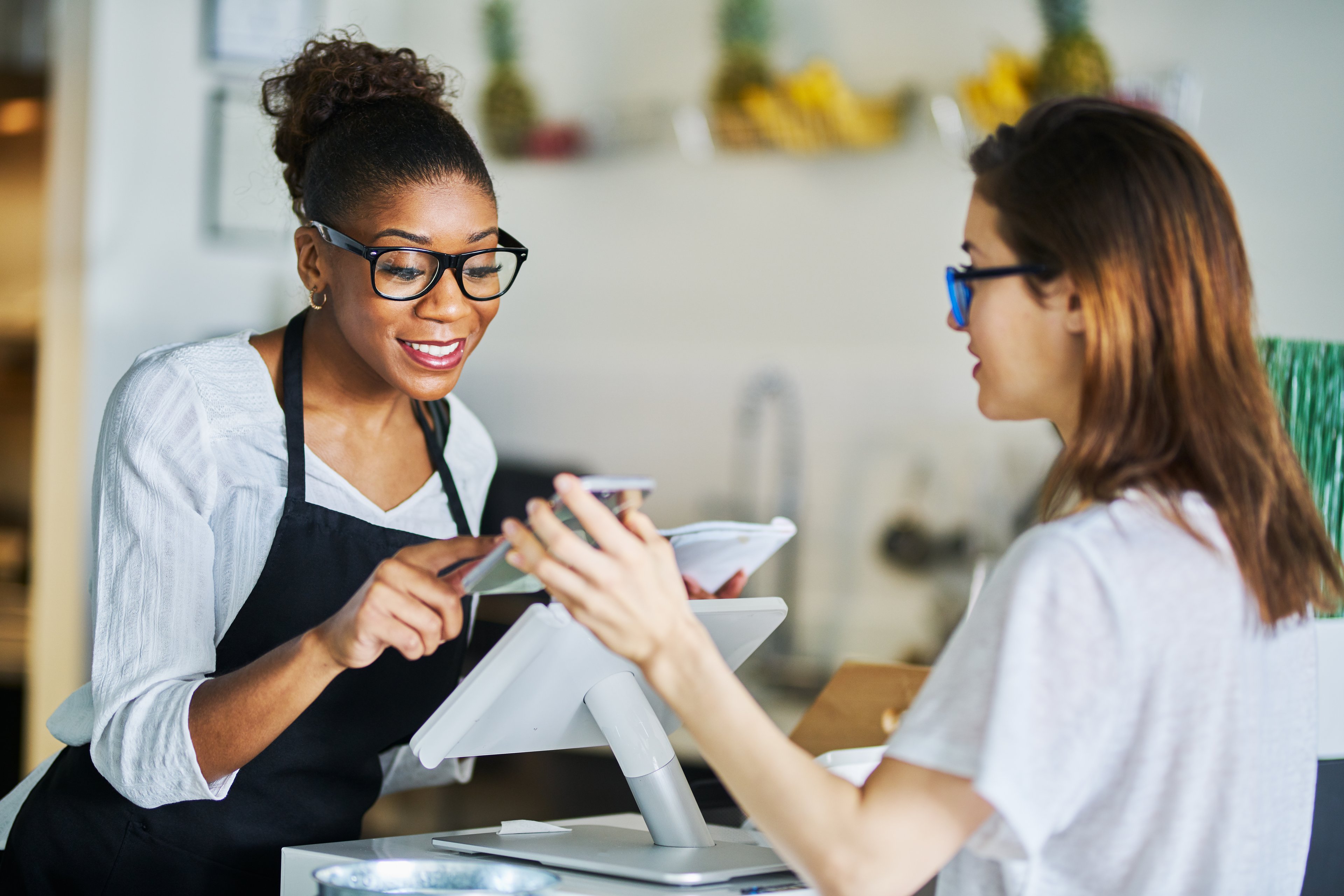 A customer pays via mobile phone at a checkout counter.