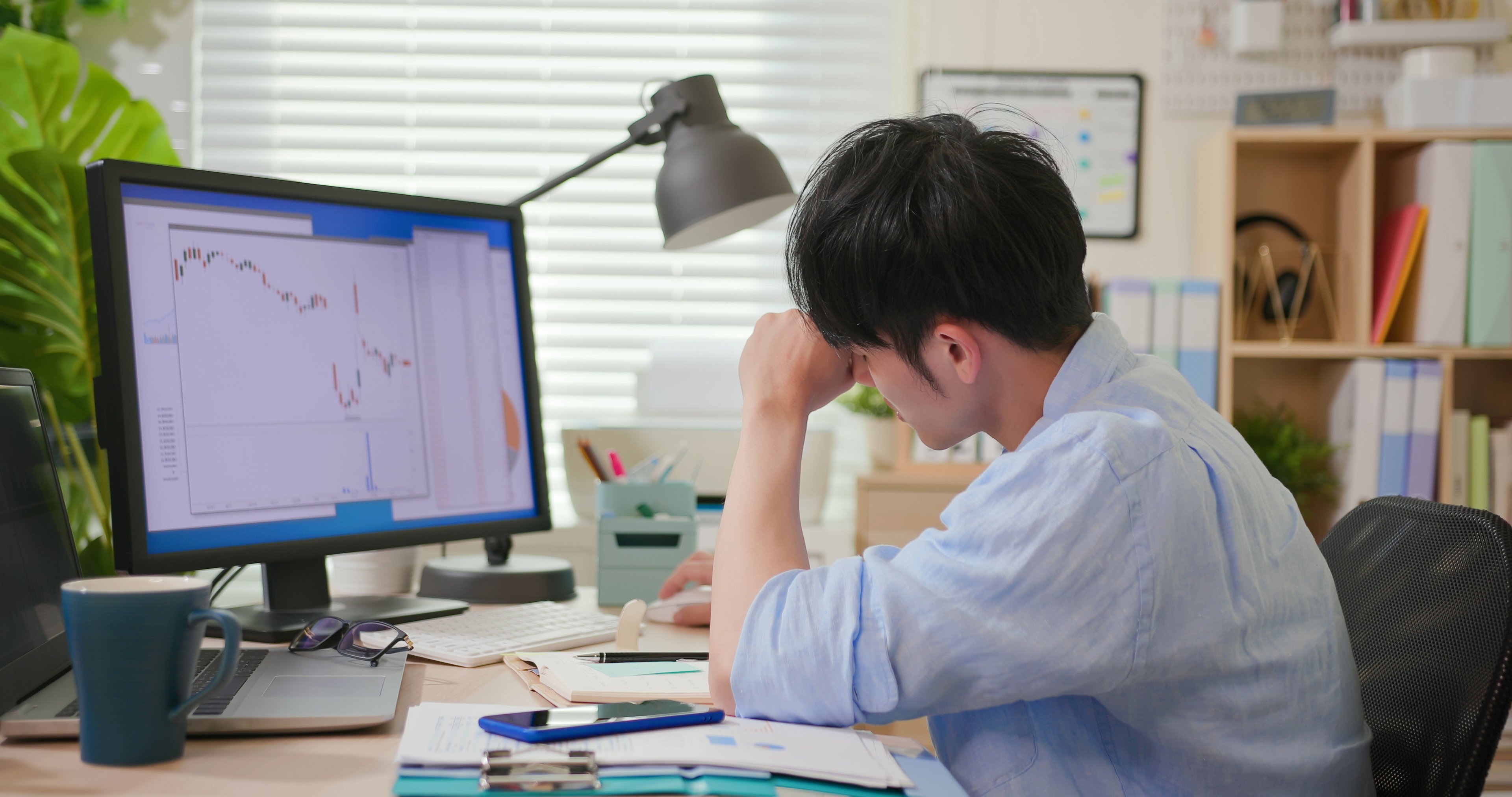 person sits at desk with stock info on computer