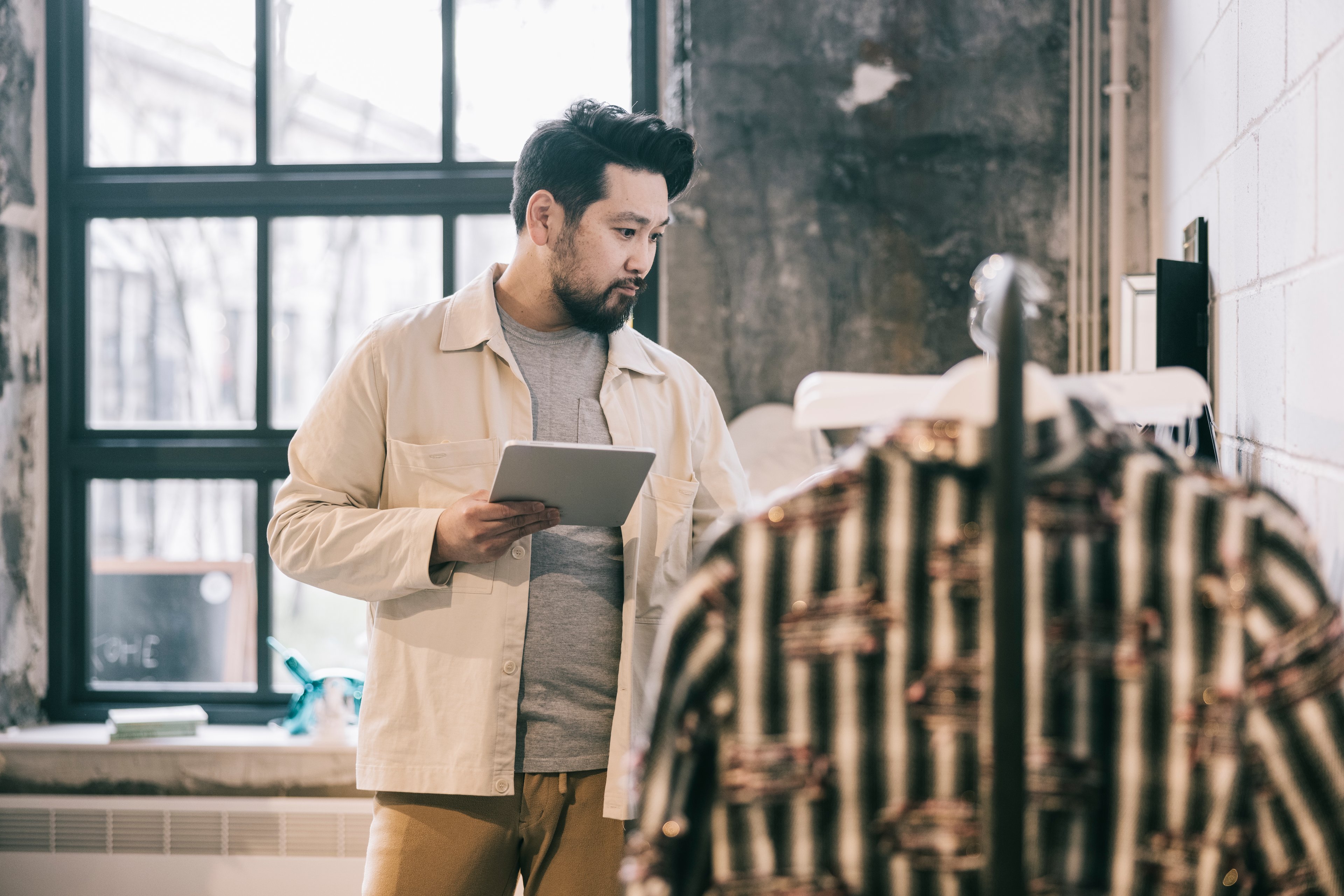 A shopper looking at a rack of shirts in a clothing store. 