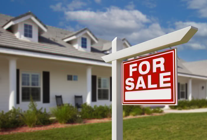 A house with a for sale sign in front of it.