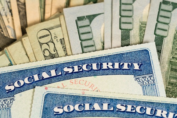 Two Social Security cards against a background of U.S. currency.