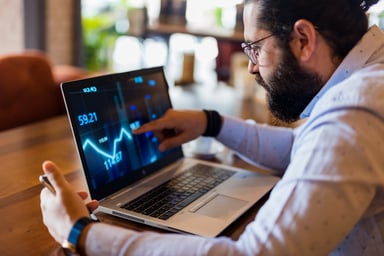 man in specs looking at a line chart on a laptop