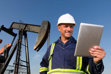 oil field worker studies a tablet.