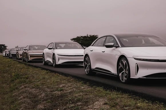 Several Lucid Air vehicles lined up on a road.