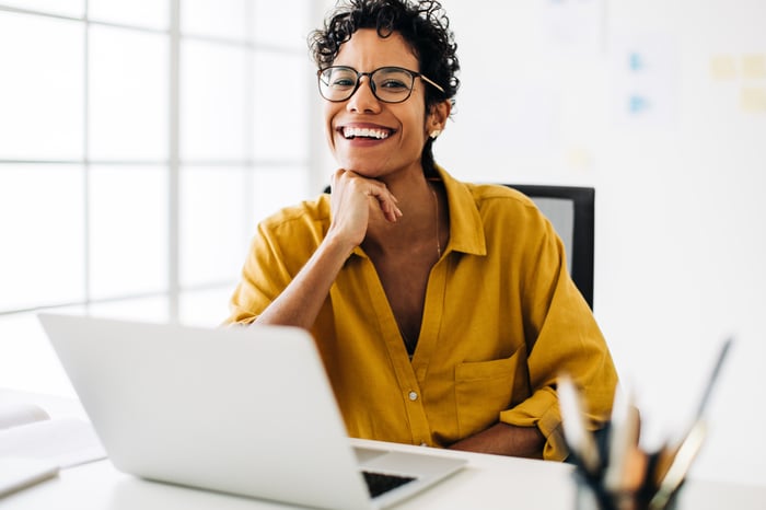 A smiling person at a laptop.