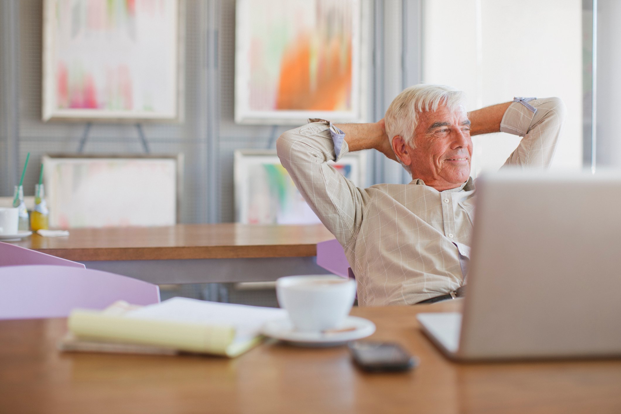 A smiling person sitting with hands behind their head.