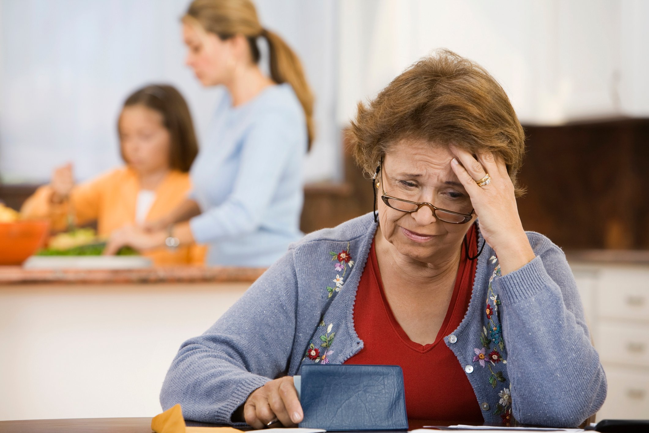 Worried person with hand on head holding checkbook.