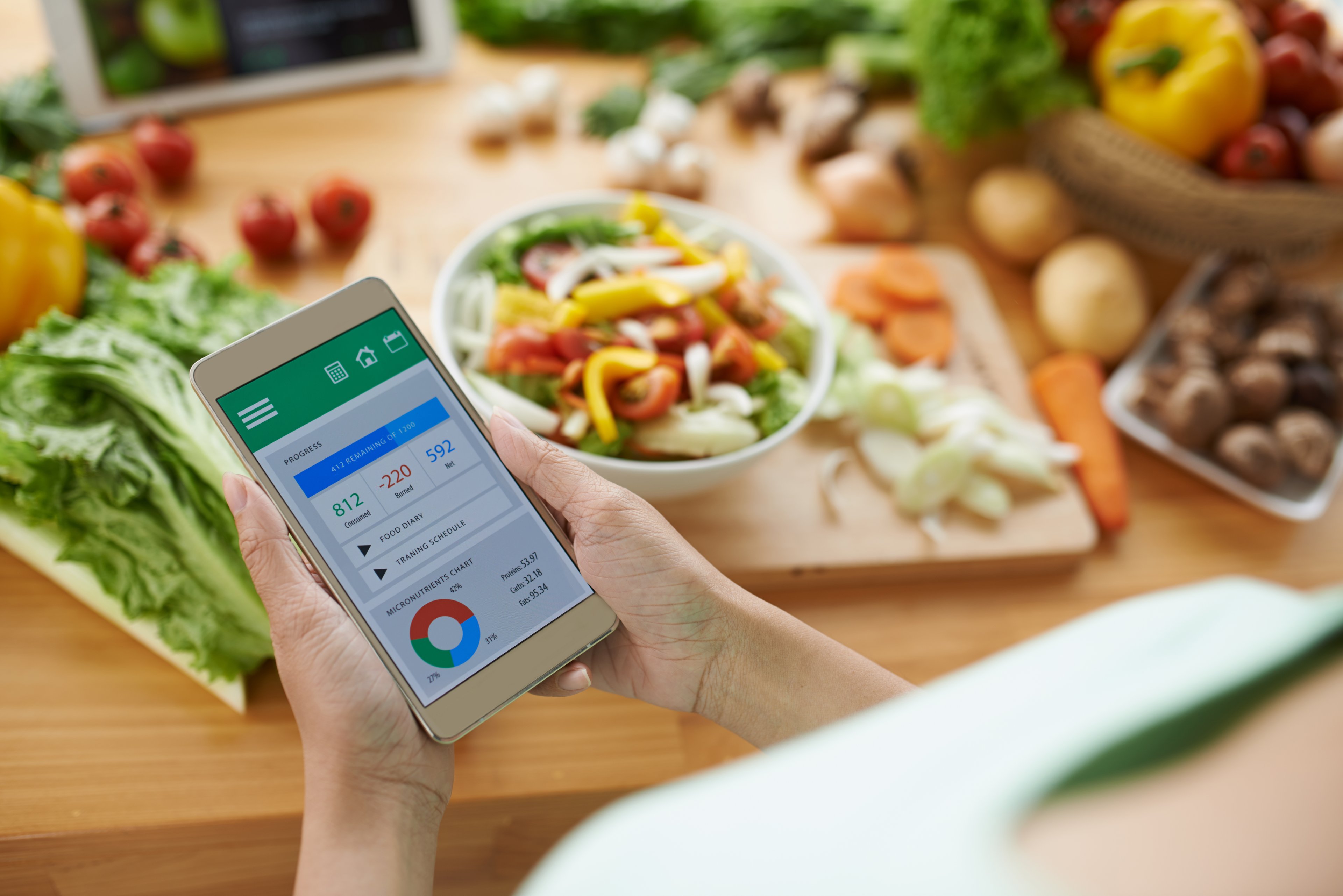 A spread of healthy foods and someone looking at a diet app