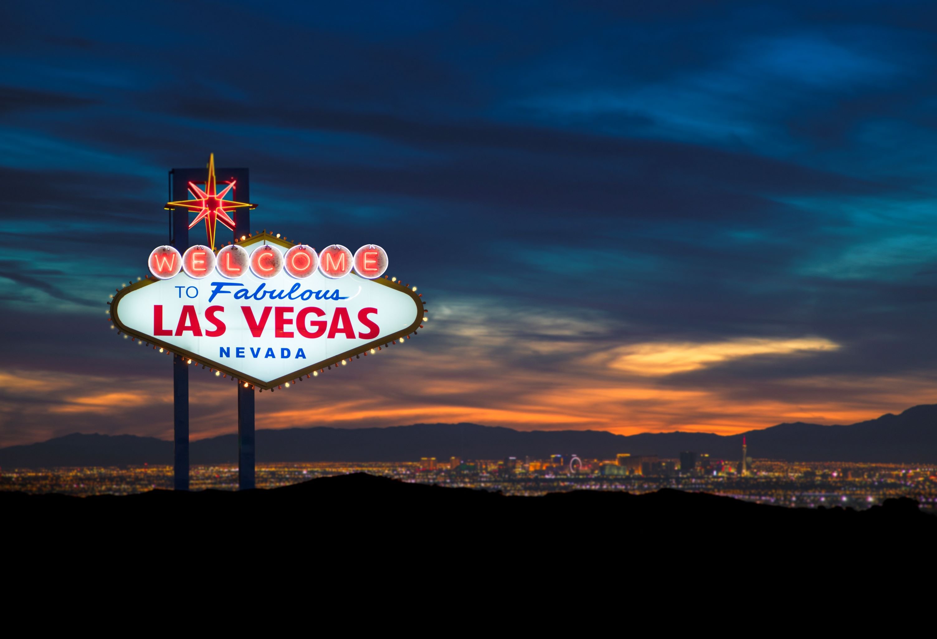 The Welcome to Las Vegas sign in front of the Las Vegas skyline.