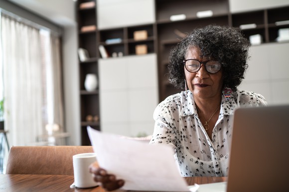 Someone sitting at a table and reading a piece of paper.