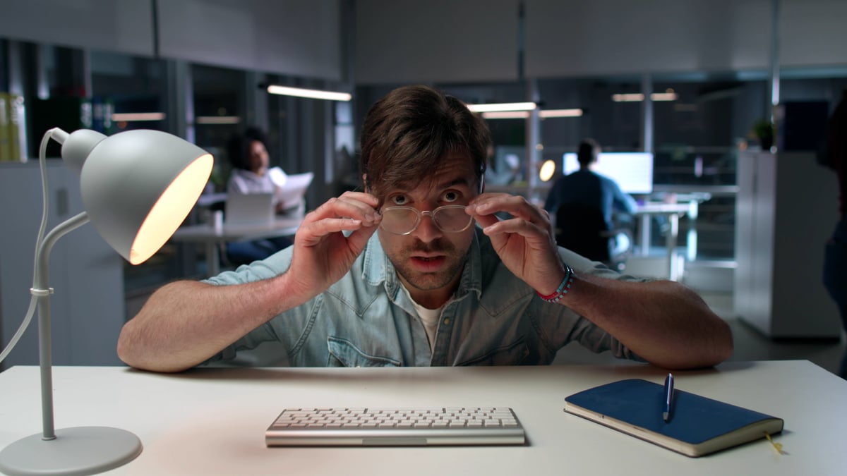 Person leaning over desk and looking over the tops of their glasses. 