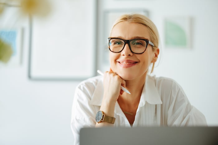 A smiling person at a laptop.