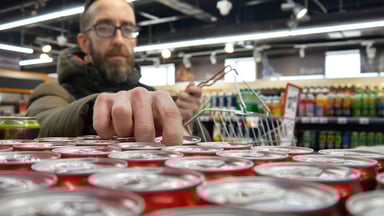Person taking a red can in a supermarket