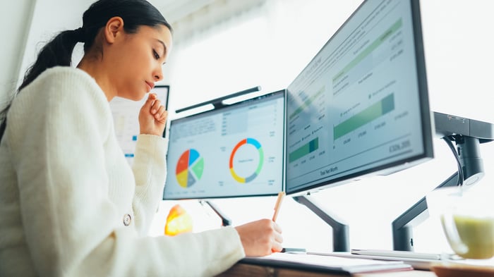 A person sits at a computer showing various graphs.