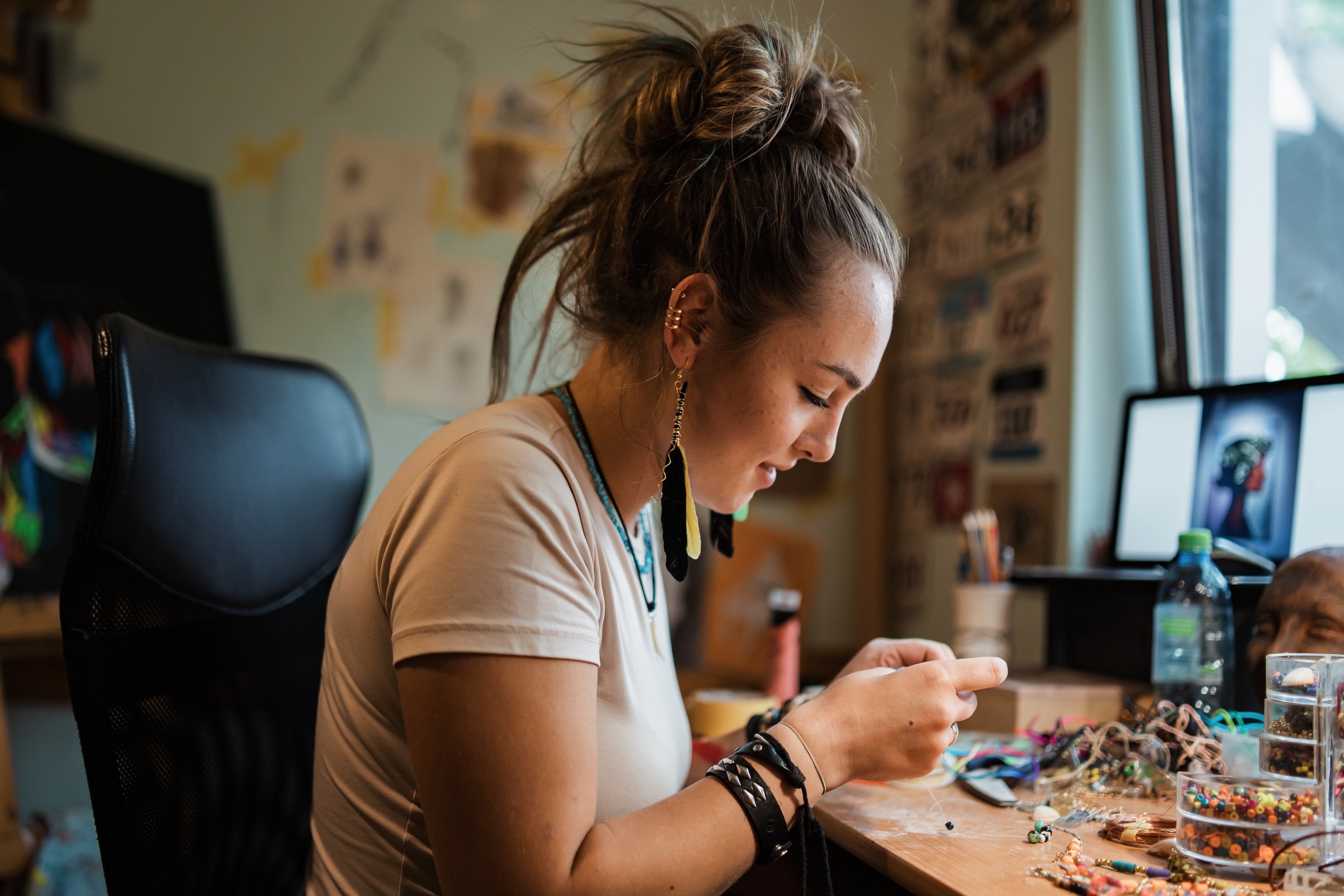 A person makes jewelry in a home workshop.