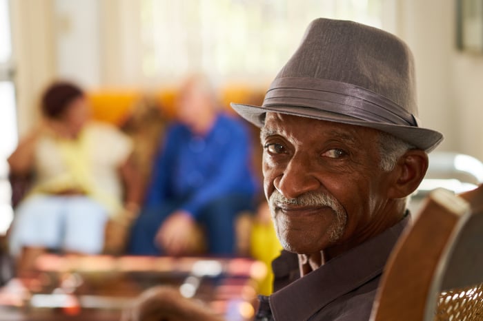 Someone in a hat is seated and smiling.