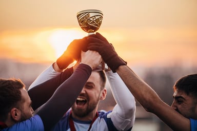 athletes hold up a golden trophy.