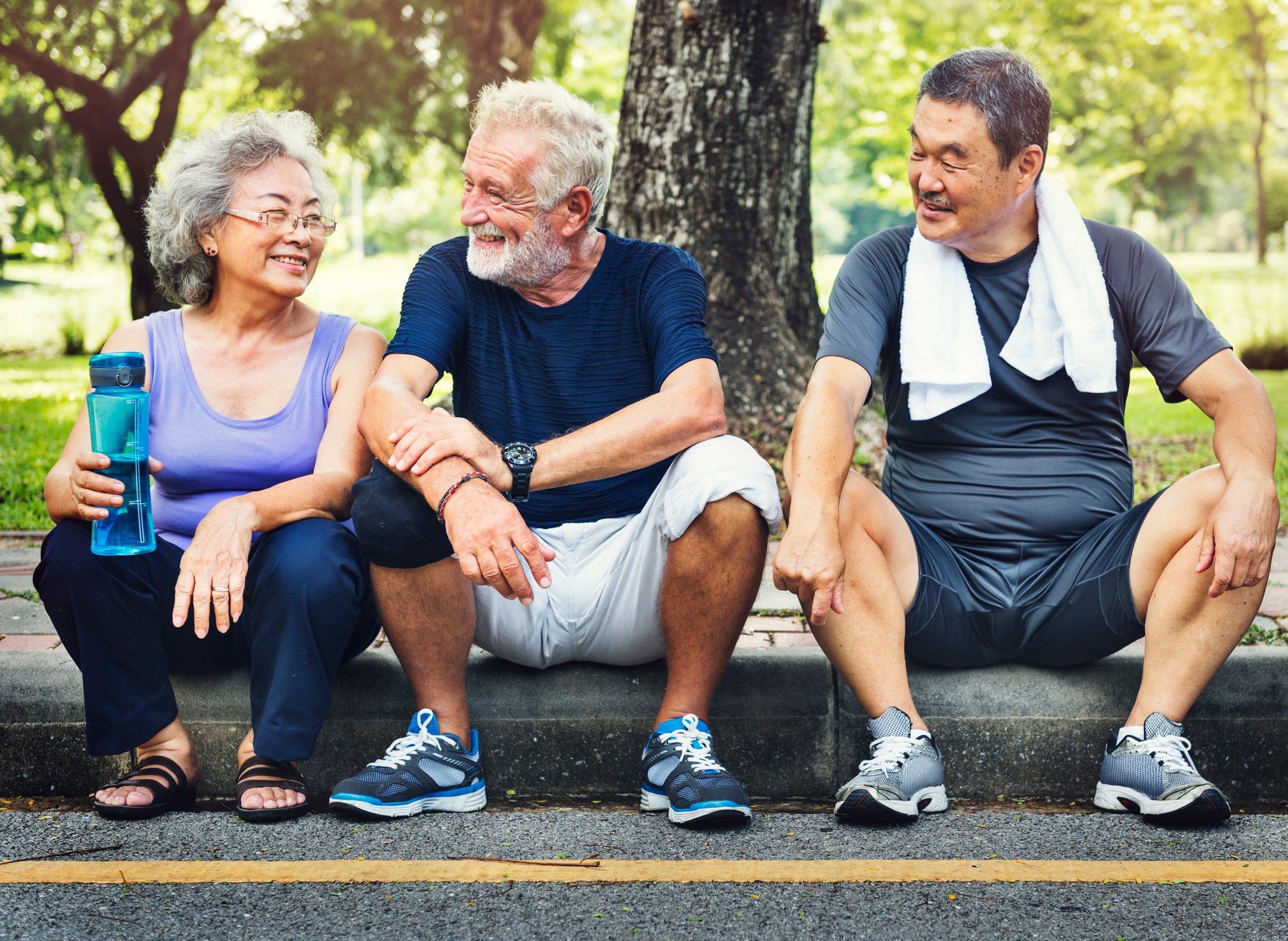 Three people sitting on a street curb.