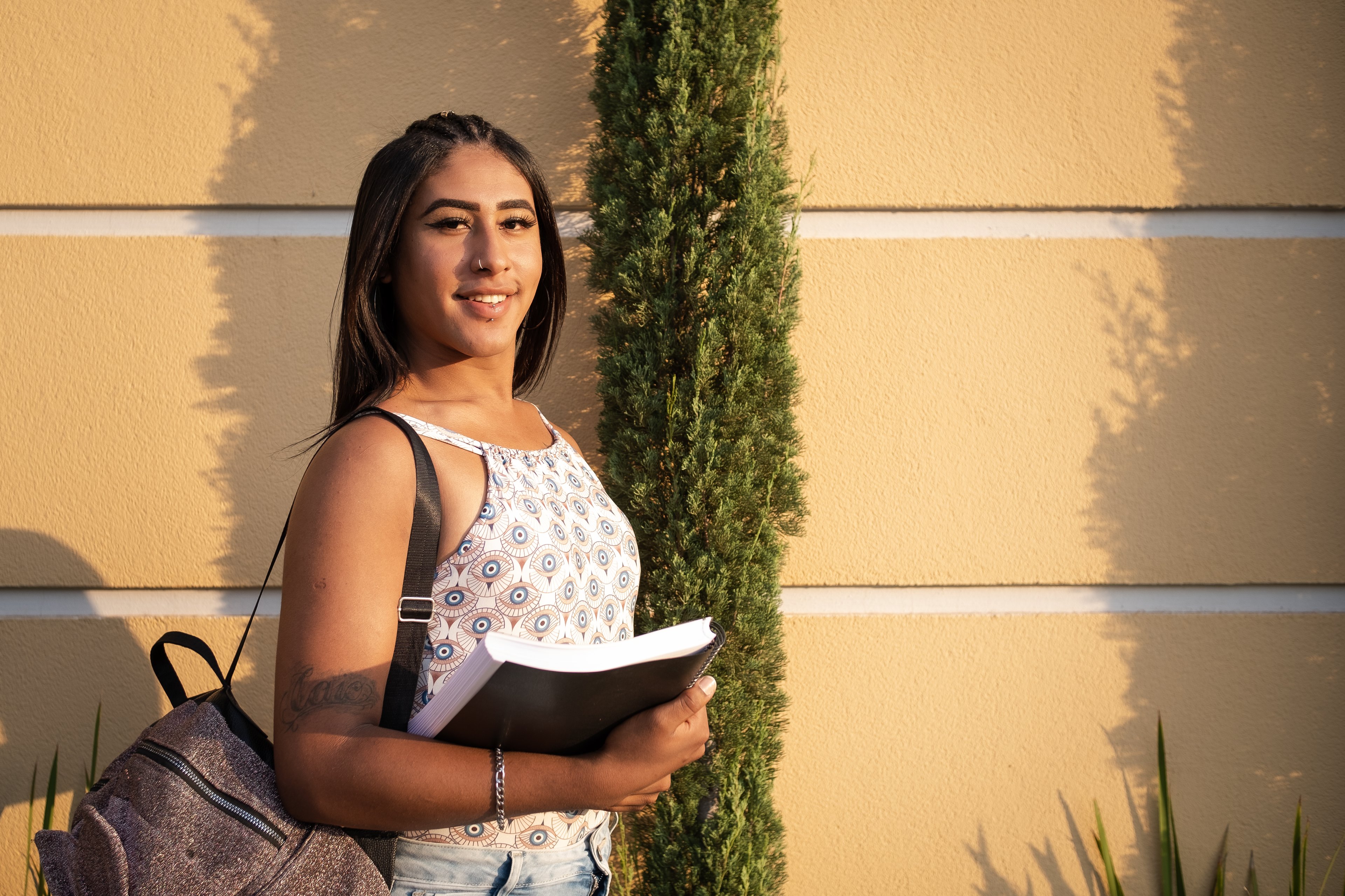 Someone holding a book while wearing a backpack.