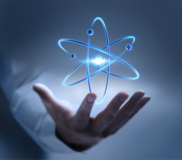 Electrons orbiting an atom above an outstretched hand. 