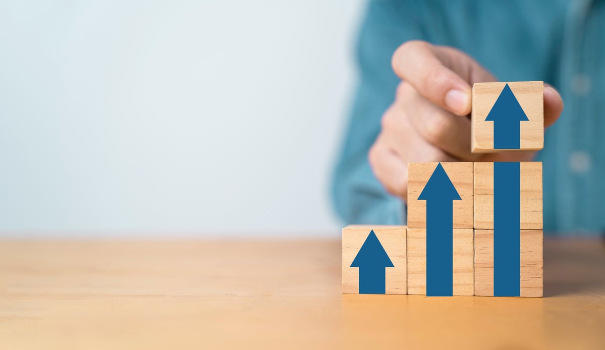 A person is stacking wooden blocks in increasingly taller towers with arrows drawn on the blocks.