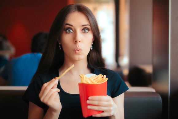 A woman eating french fries.