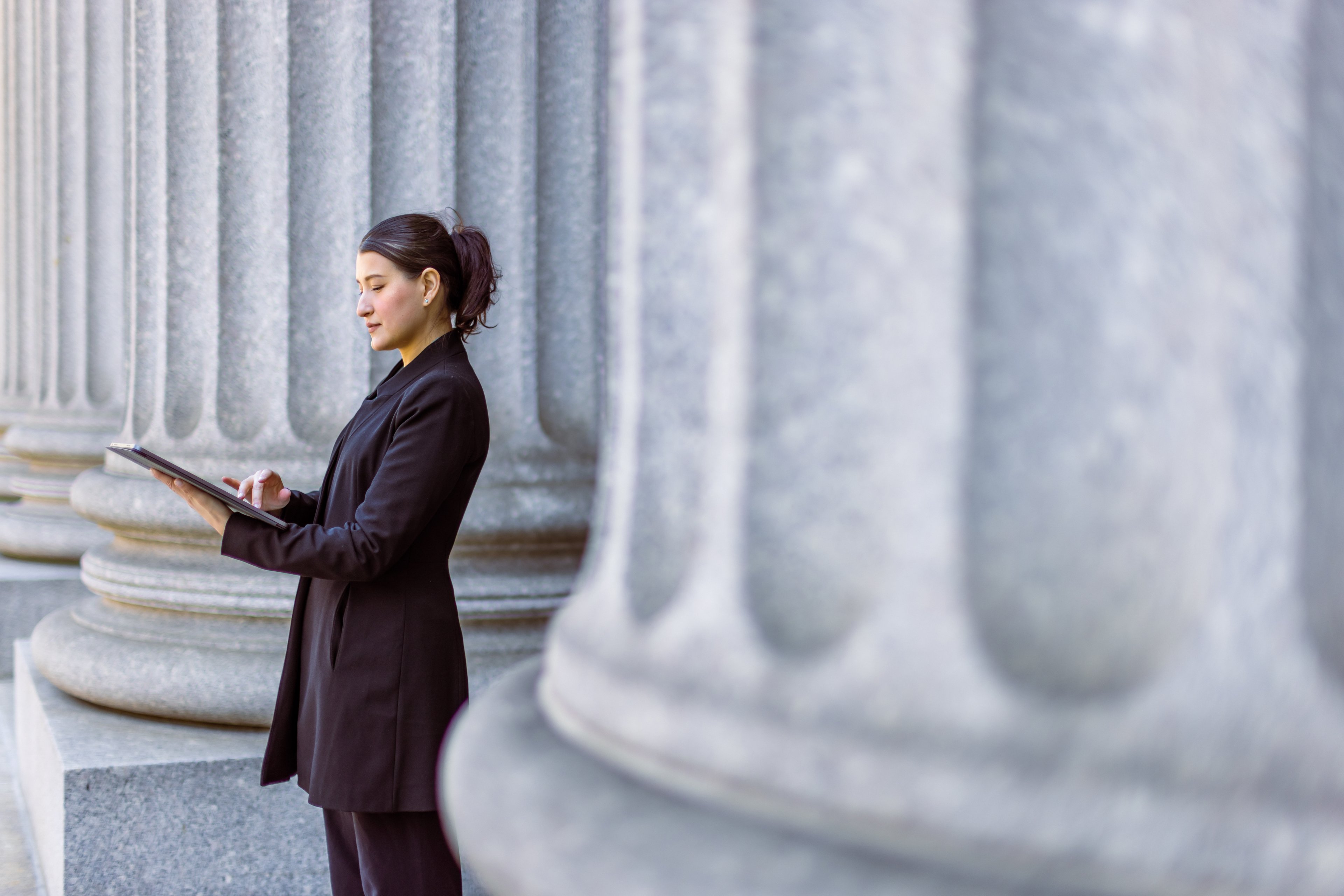 Person standing outside building looking at tablet.