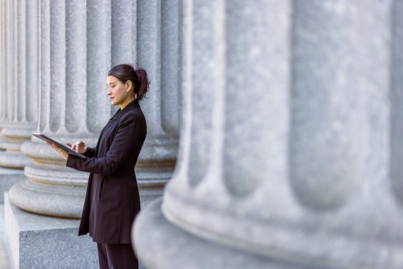 Person standing outside building looking at tablet.