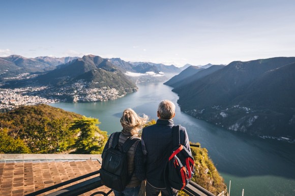 Retirees staring out at a river flowing through a mountain range.